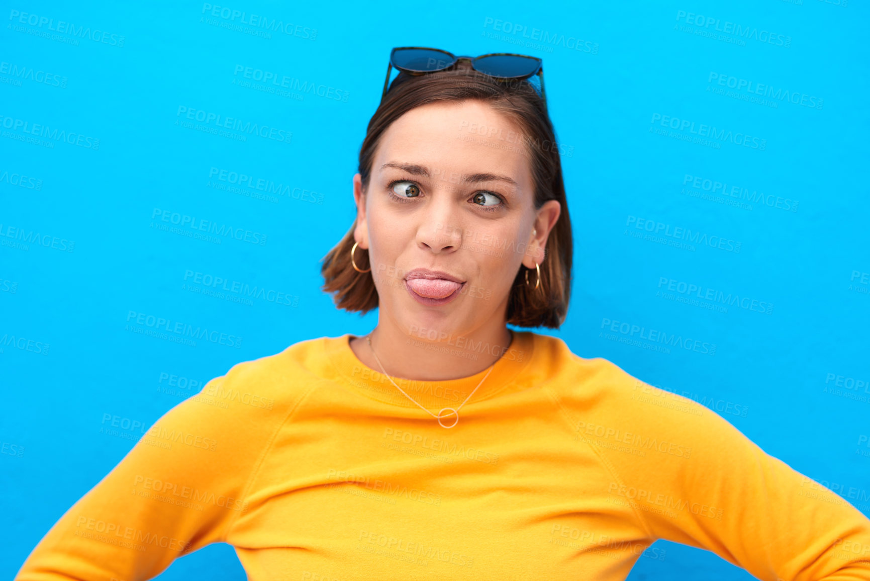 Buy stock photo Cropped shot of a young woman making faces against a blue background