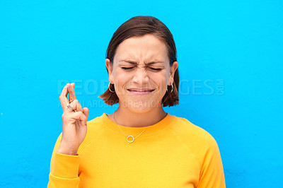 Buy stock photo Cropped shot of a young woman crossing fingers against a blue background