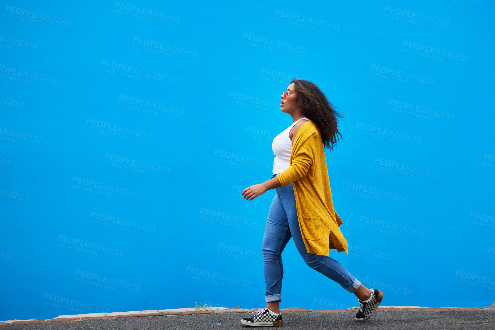 Buy stock photo Full length shot of an attractive young woman walking against a blue background