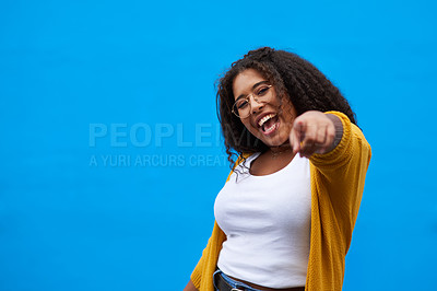 Buy stock photo Cropped portrait of an attractive young woman pointing against a blue background