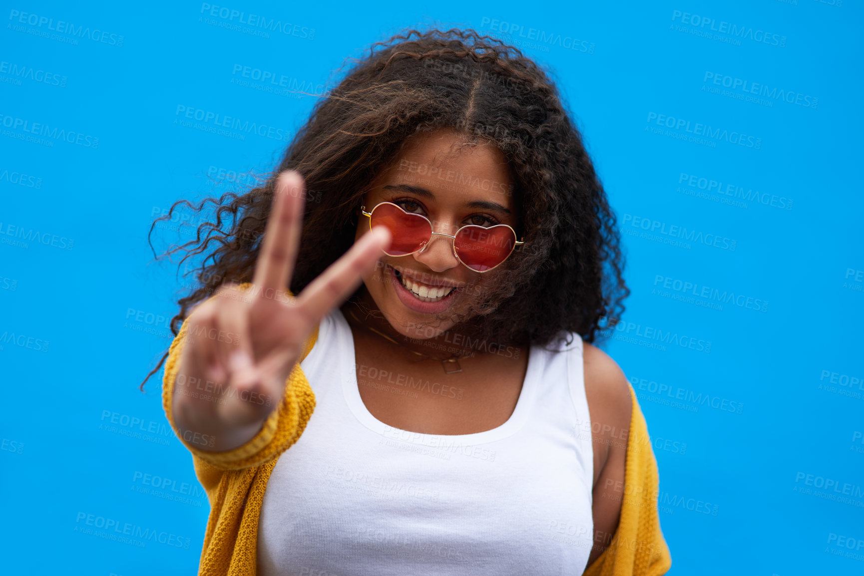 Buy stock photo Cropped portrait of an attractive young woman showing the peace sign against a blue background