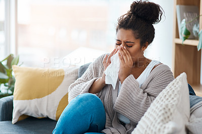 Buy stock photo Cropped shot of a young woman blowing her nose with a tissue at home