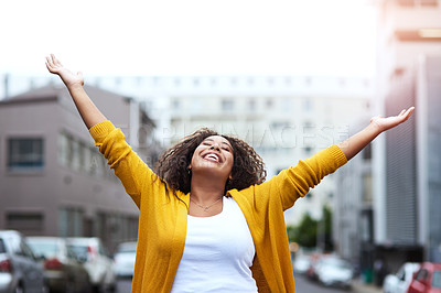 Buy stock photo Cropped shot of a happy young woman celebrating with arms raised against a city background