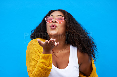 Buy stock photo Studio portrait of an attractive young woman blowing a kiss against a blue background
