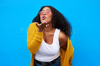 Buy stock photo Studio portrait of an attractive young woman blowing a kiss against a blue background
