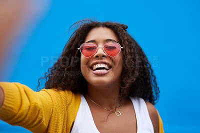 Buy stock photo Portrait, smile and woman with selfie in studio for photography, heart glasses and social media post. Happy, girl and love sunglasses of profile picture, blog update and influencer on blue background