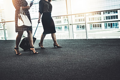 Buy stock photo Cropped shot of two unrecognizable businesswomen walking together with their bags in a modern workplace