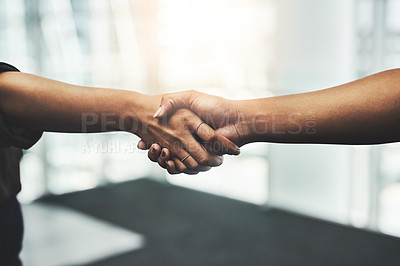 Buy stock photo Closeup shot of two unrecognizable businesswomen shaking hands while standing in a modern workplace