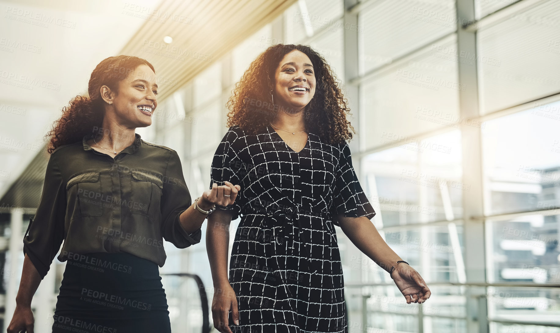 Buy stock photo Cropped shot of two attractive young businesswomen walking through a modern workplace