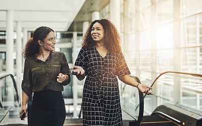 Buy stock photo Cropped shot of two attractive young businesswomen walking through a modern workplace