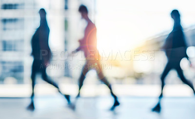 Buy stock photo Shot of a group of unrecognizable businesspeople walking inside of the office during the day