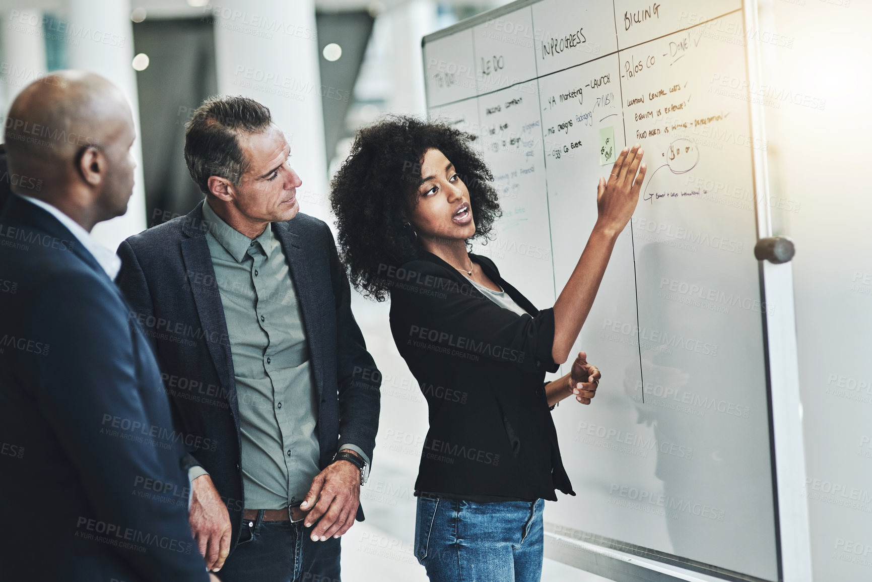 Buy stock photo Shot of a group of confident businesspeople having a meeting while explaining on a white board inside of the office