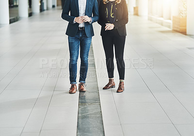 Buy stock photo Low angle shot of a two unrecognizable businesspeople walking around at work during the day