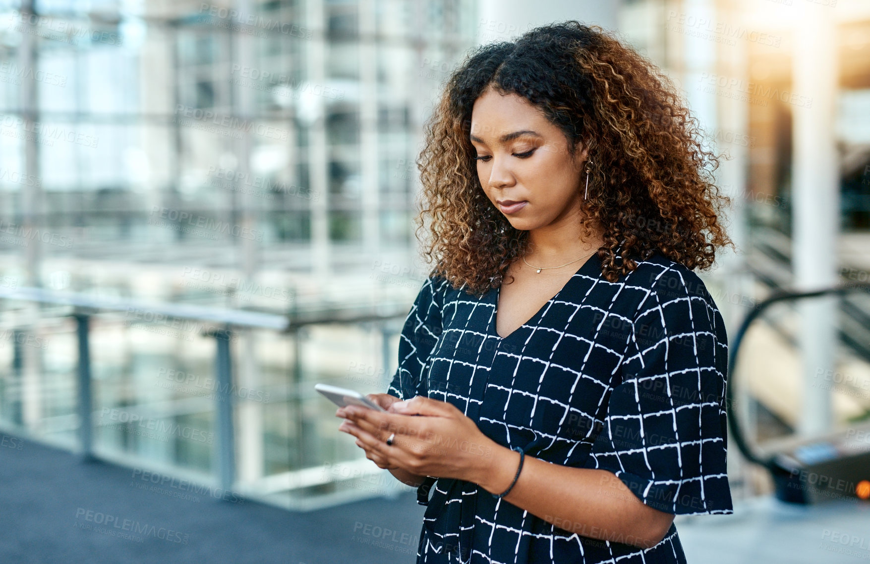 Buy stock photo Cropped shot of an attractive young businesswoman using a smartphone in a modern office