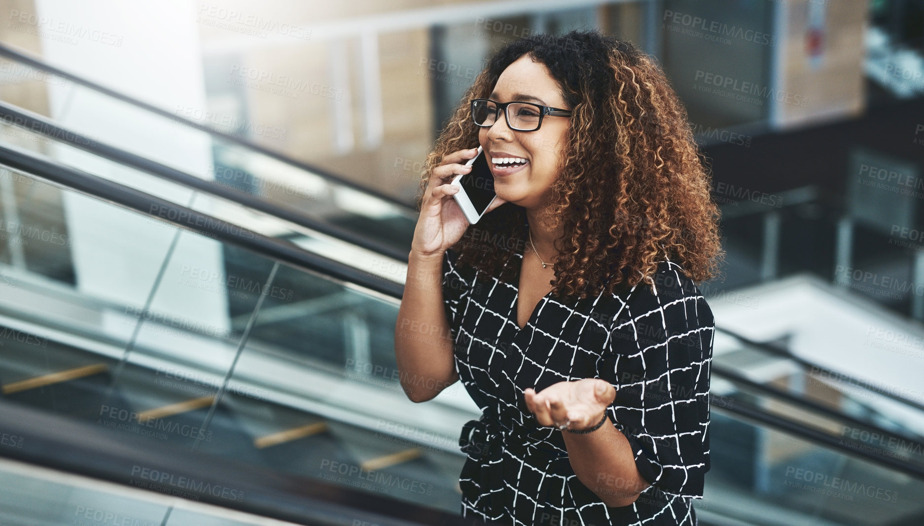 Buy stock photo Cropped shot of an attractive young businesswoman taking a phonecall while moving up an escalator in a modern workplace