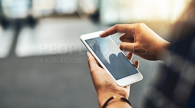 Buy stock photo Cropped shot of an unrecognizable businesswoman using a smartphone while standing in a modern office
