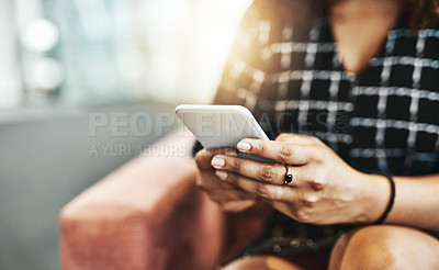 Buy stock photo Cropped shot of an unrecognizable businesswoman using a smartphone while sitting on a couch in a modern office