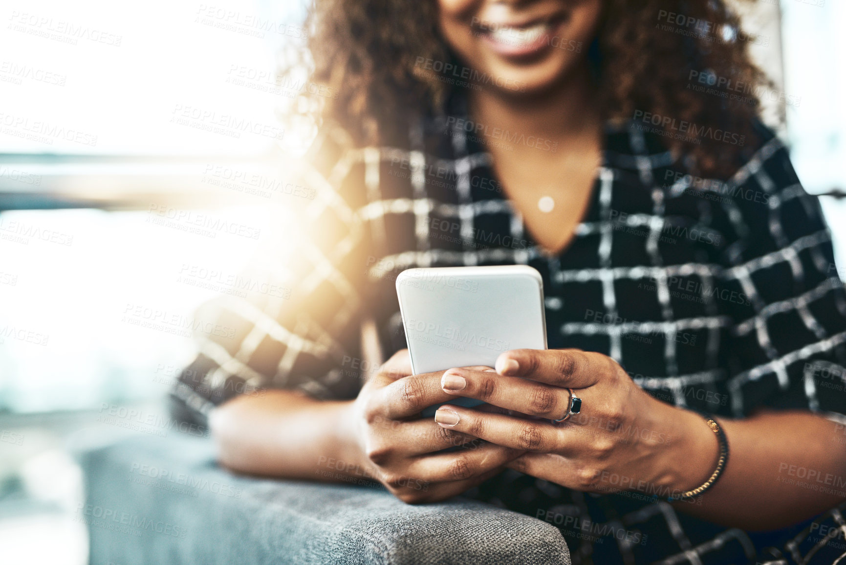 Buy stock photo Cropped shot of an unrecognizable businesswoman using a smartphone while sitting on a couch in a modern office