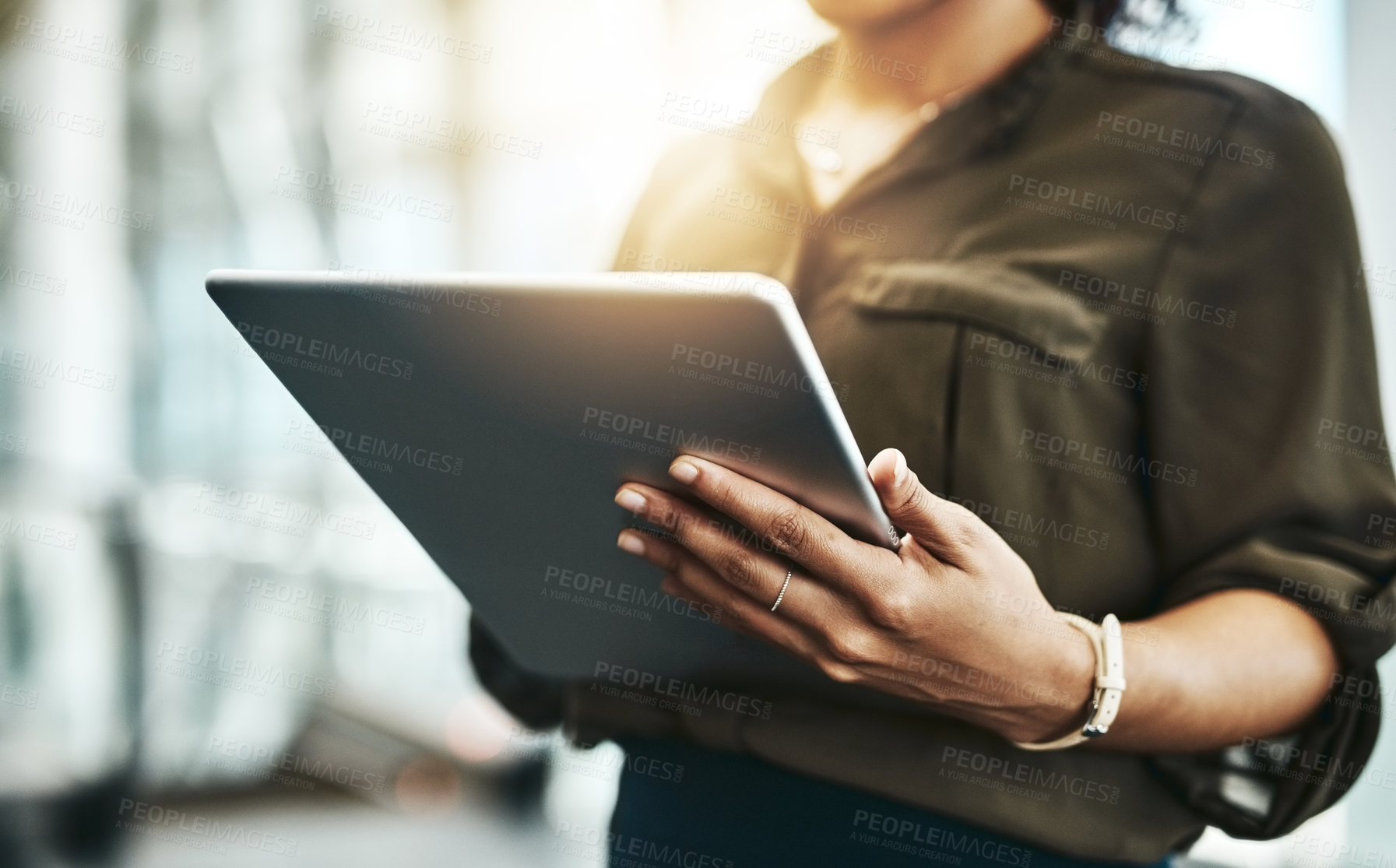Buy stock photo Cropped shot of an unrecognizable businesswoman using a digital tablet while standing in a modern office
