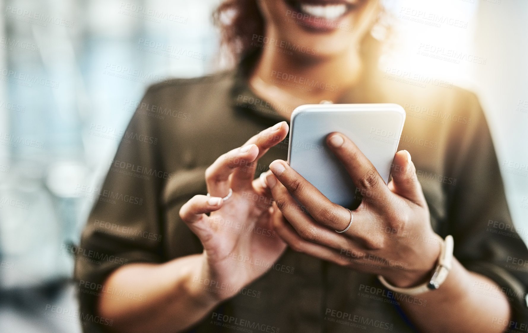 Buy stock photo Cropped shot of an unrecognizable businesswoman using a smartphone while standing in a modern office