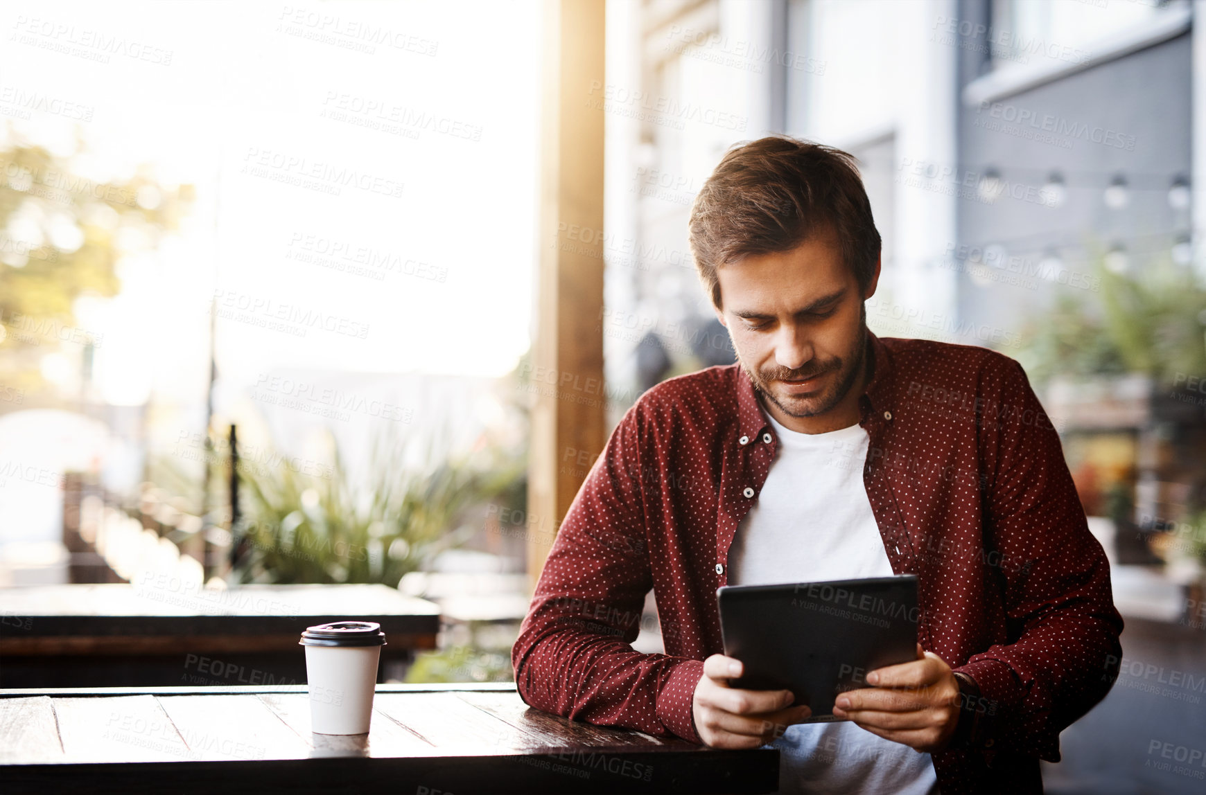 Buy stock photo Cropped shot of a handsome young man using his digital tablet outside
