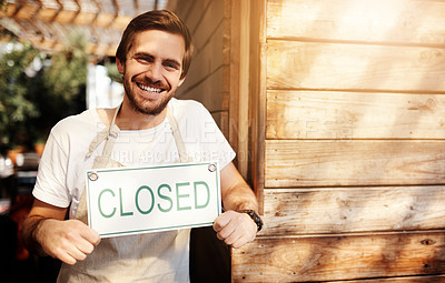 Buy stock photo Cropped portrait of a handsome young male business owner holding up a sign in the doorway of his coffee shop