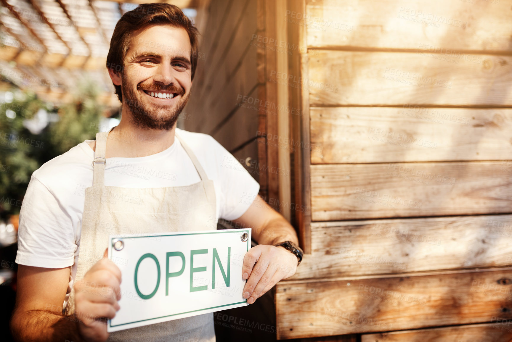 Buy stock photo Cropped portrait of a handsome young male business owner holding up a sign in the doorway of his coffee shop