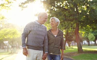 Buy stock photo Senior couple, walking and holding hands outdoor at a park with love, care and support. A elderly man and woman in nature for a walk, quality time and communication for healthy marriage or retirement