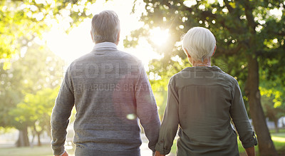 Buy stock photo Senior couple, walking and outdoor at a park with a love, care and support from back. A elderly man and woman holding hands in nature for a walk, quality time and healthy marriage or retirement