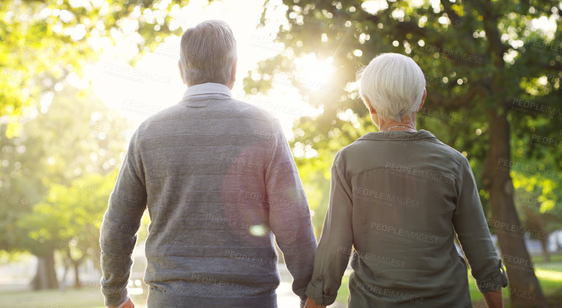 Buy stock photo Senior couple, walking and outdoor at a park with a love, care and support from back. A elderly man and woman holding hands in nature for a walk, quality time and healthy marriage or retirement