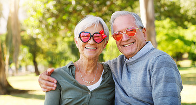 Buy stock photo Senior couple, funny glasses and portrait outdoor at a park with love, care and heart shape. A elderly man and woman with comic sunglasses in nature for happiness, healthy marriage and retirement