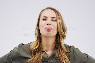 Buy stock photo Portrait, comic and tongue with a woman in studio on a gray background looking silly or goofy. Comedy, funny face and crazy with a playful young female person joking indoor for carefree, fun or humor