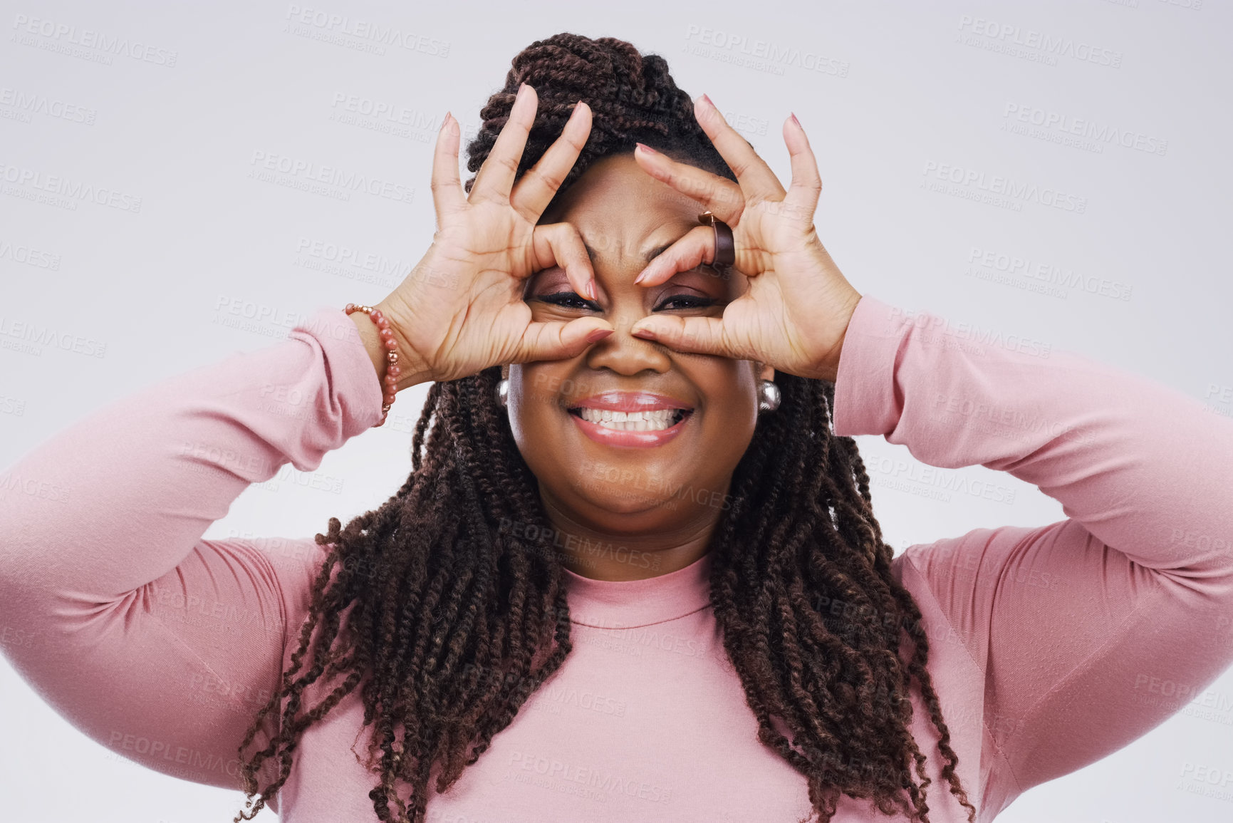 Buy stock photo Portrait, funny face and finger mask with a black woman laughing in studio on a white background for humor. Comic, comedy and hands as glasses with a playful young female person joking or having fun