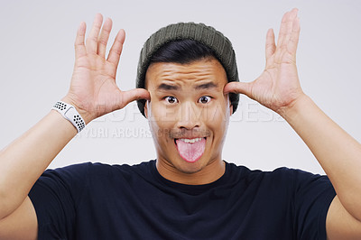 Buy stock photo Funny face, portrait and Asian man in studio with tongue out, hands and silly on white background. Male person, comic and casual fashion for comedy, humor and making fun and goofy personality