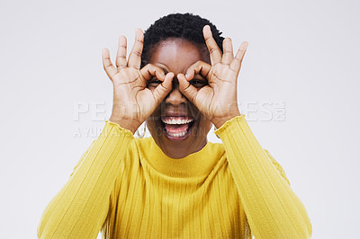 Buy stock photo Portrait, funny face and finger glasses with a black woman laughing in studio on a white background for humor. Comic, comedy and hands on eyes with a playful young female person joking or having fun