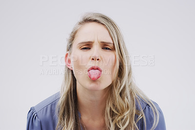 Buy stock photo Studio shot of a young woman making a funny face against a gray background
