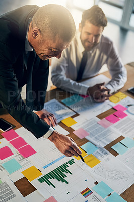 Buy stock photo Cropped shot of two businessmen going over paperwork during a meeting in their office