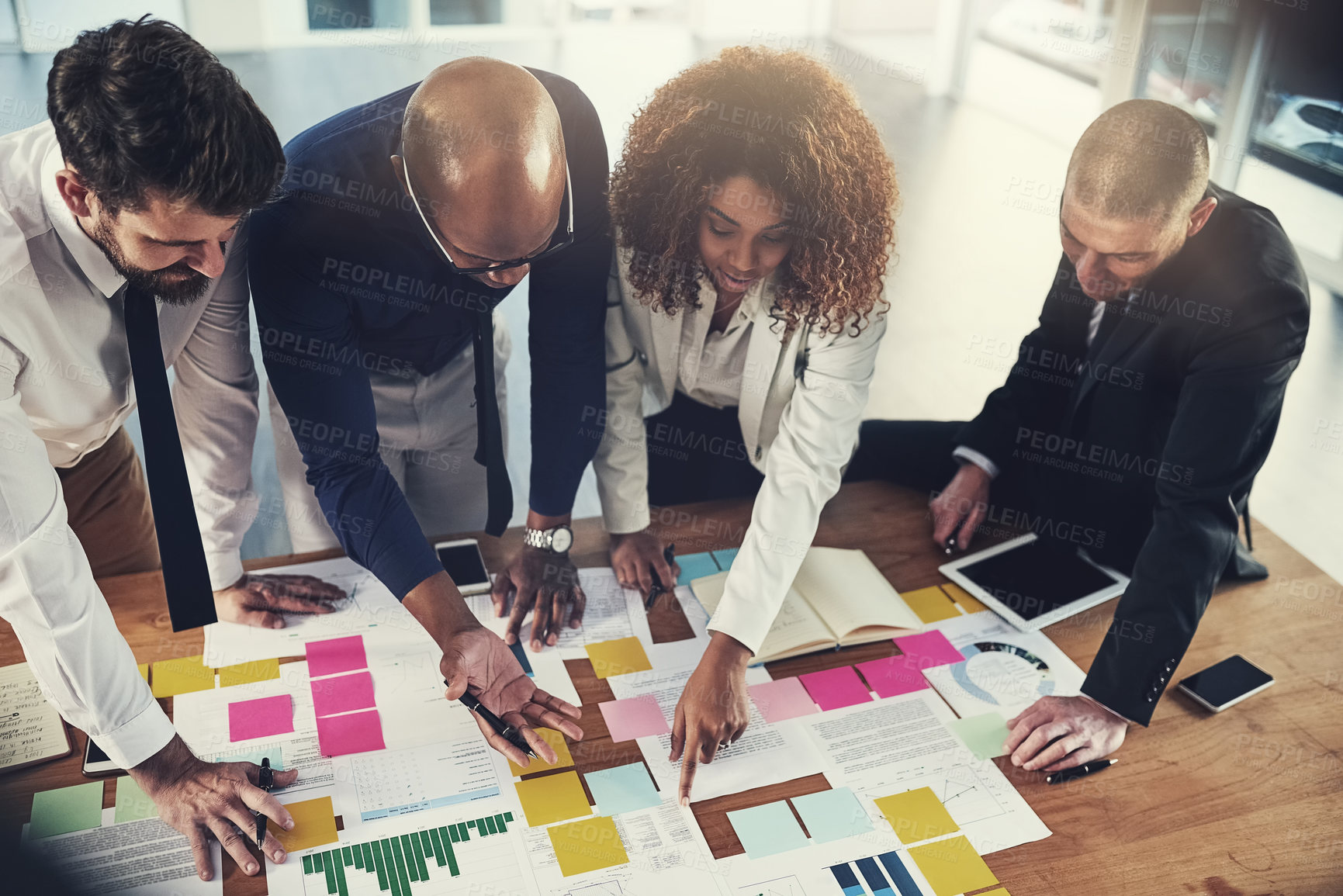 Buy stock photo Cropped shot of a group of businesspeople going over paperwork during a meeting in their office