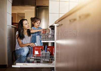 Buy stock photo Shot of a cute little girl and her mother loading the dishwasher together at home