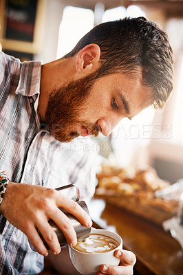 Buy stock photo A cropped shot of a barista pouring frothy milk into a cup of hot coffee turning it into a picture