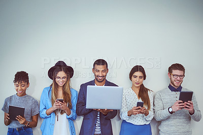 Buy stock photo Studio shot of a group of young businesspeople using wireless technology while standing in line against a grey background