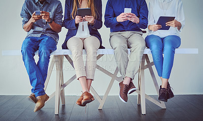 Buy stock photo Studio shot of a group of unrecognizable businesspeople using wireless technology while sitting in line against a grey background