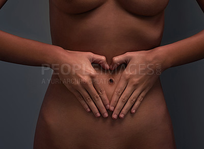 Buy stock photo Shot of an unrecognizable woman posing with her hands on her stomach against a dark background