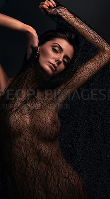 Buy stock photo Studio shot of a beautiful young woman covered only in netting against a dark background