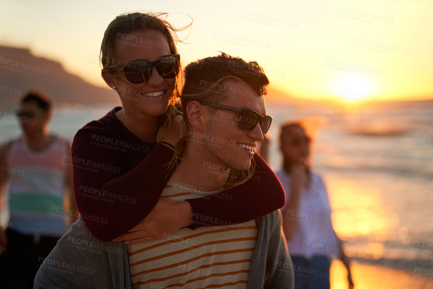 Buy stock photo Cropped shot of an affectionate young man piggybacking his girlfriend on the beach