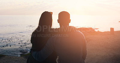 Buy stock photo Rearview shot of an unrecognizable affectionate couple watching the sunset at the beach