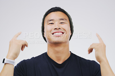 Buy stock photo Asian man, portrait and pointing in studio for happiness, announcement and sign on backdrop for Promotion. Male person, direction and smile by white background for vote, info and product review