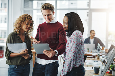 Buy stock photo Shot of a group of colleagues using a digital tablet together in a modern office