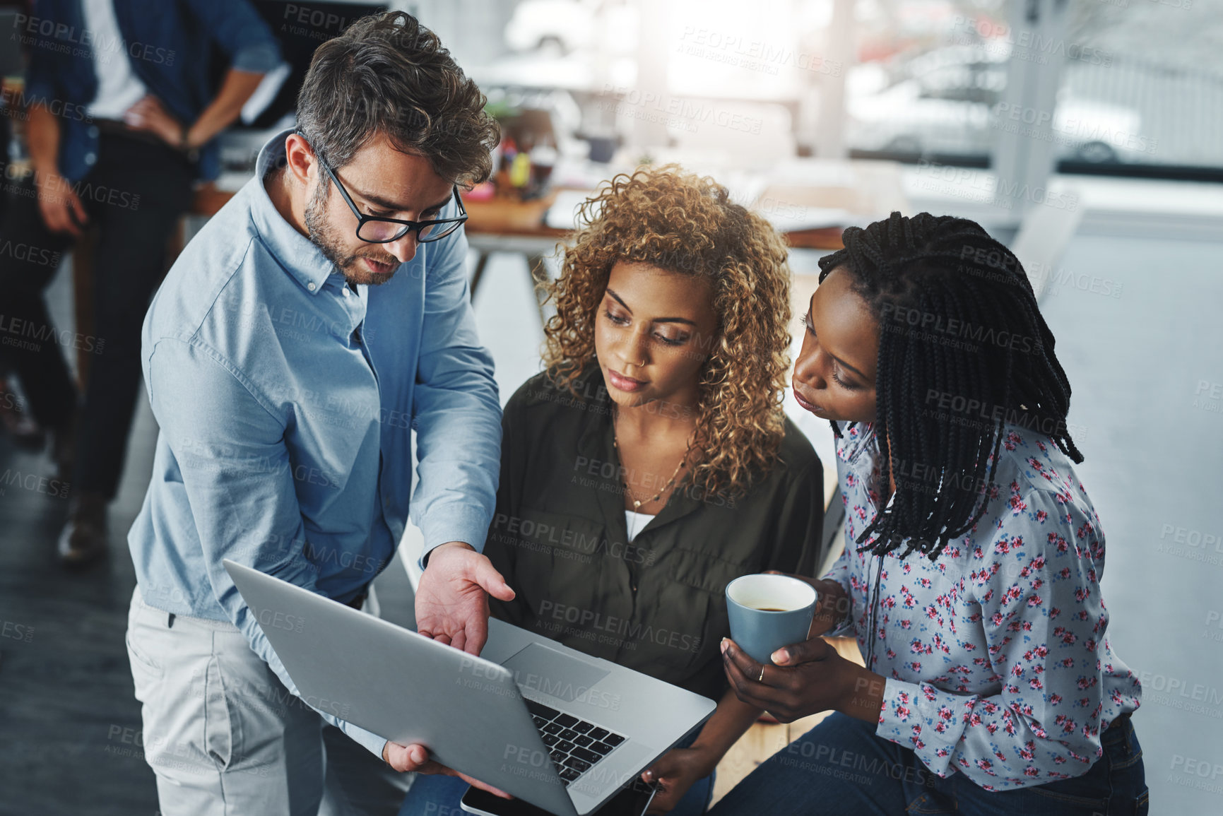 Buy stock photo Shot of a group of colleagues using a laptop together in a modern office