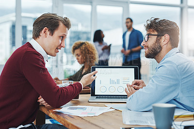 Buy stock photo Shot of two young colleagues using a laptop together in a modern office